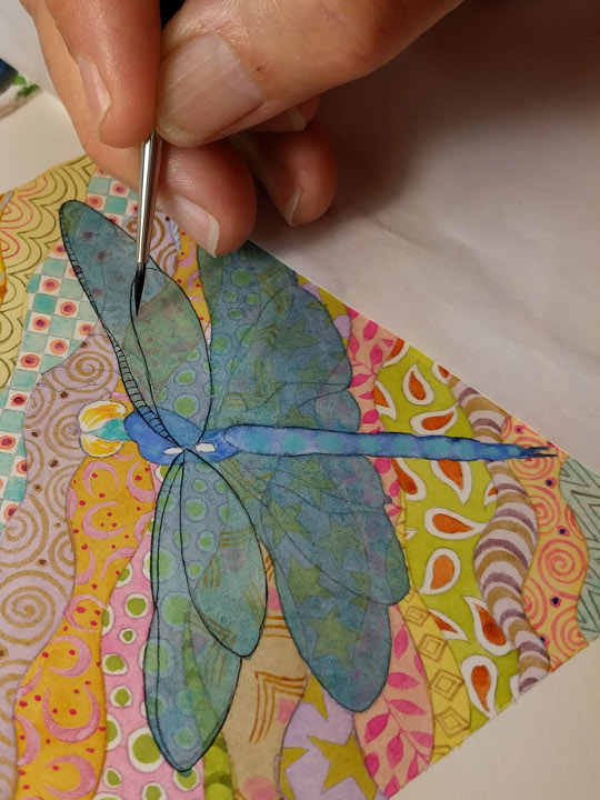 Molly's hand painting a dragonfly